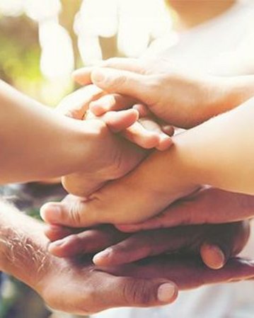 Verschiedene Hände, die übereinander gestapelt sind, symbolisieren Zusammenarbeit und Gemeinschaft.