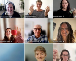 Neun Personen in einem virtuellen Meeting, jede hält ein Objekt in der Hand. Einige zeigen Lebensmittel, andere Alltagsgegenstände.