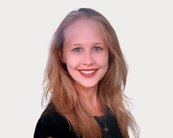 Eine lächelnde Frau mit langen, blonden Haaren und blauen Augen trägt ein schwarzes Oberteil. Der Hintergrund ist neutral.
