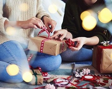 Menschen sitzen auf dem Boden und öffnen Geschenke